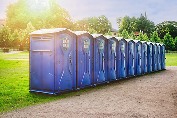 Image showing Row of Blue Portable Toilets in Park