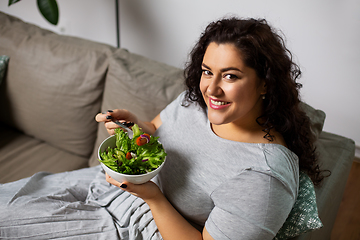 Image showing smiling young woman eating vegetable salad at home