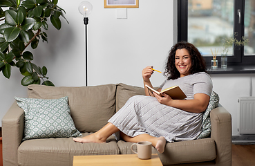 Image showing happy young woman with diary on sofa at home