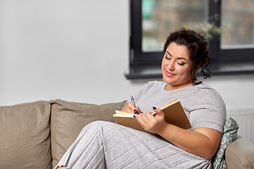 Image showing happy young woman with diary on sofa at home