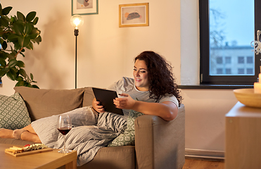 Image showing woman with tablet pc, red wine and snacks at home