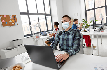 Image showing man in medical mask with laptop working at office