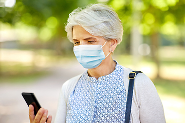 Image showing old woman in medical mask with smartphone at park