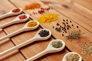 Image showing spoons with different spices on wooden table