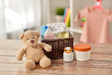 Image showing baby things in basket and teddy bear toy on table