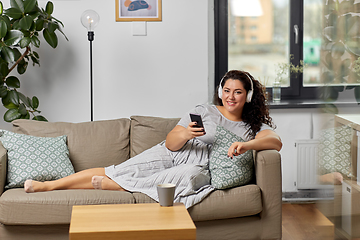 Image showing woman in headphones listens to music on smartphone