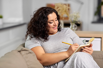 Image showing happy young woman with diary on sofa at home