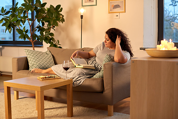 Image showing woman reading book at home in evening