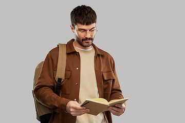 Image showing young man with backpack reading diary