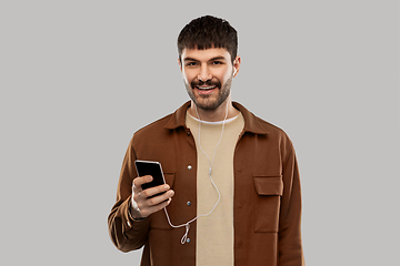 Image showing smiling young man with earphones and smartphone