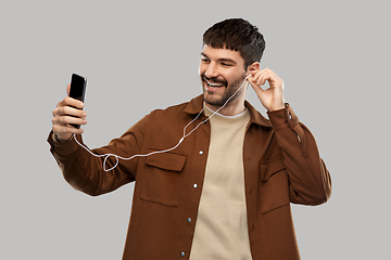 Image showing smiling young man with earphones and smartphone