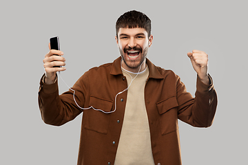 Image showing smiling young man with earphones and smartphone