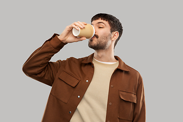 Image showing happy young man drinking coffee from takeaway cup