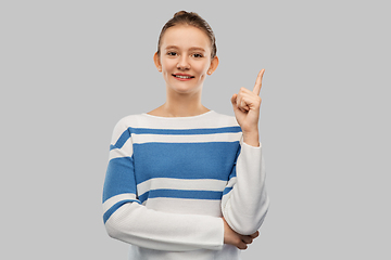 Image showing happy teenage girl in pullover pointing finger up