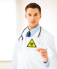 Image showing male doctor holding boihazard caution sign