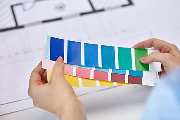 Image showing designer's hands with color palettes and blueprint