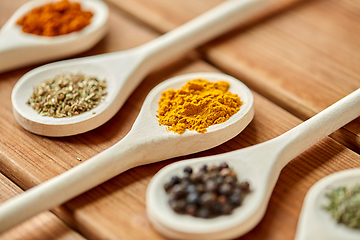 Image showing spoons with different spices on wooden table