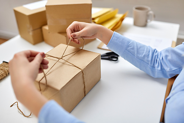 Image showing woman packing parcel and tying rope at post office