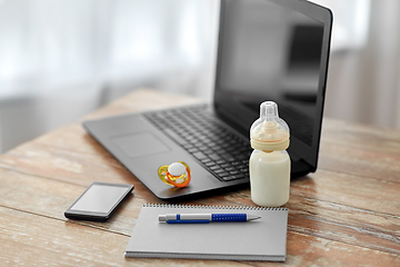 Image showing baby milk formula, laptop and notebook on table