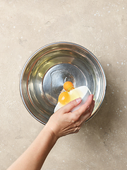 Image showing cook pours eggs into a metal bowl