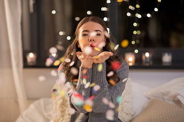 Image showing woman blowing confetti from her hands at home