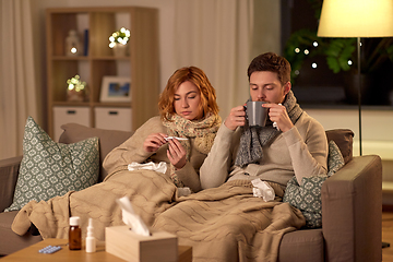 Image showing sick couple with thermometer and tea at home