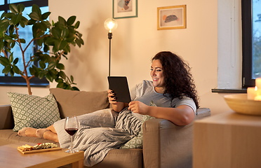 Image showing woman with tablet pc, red wine and snacks at home