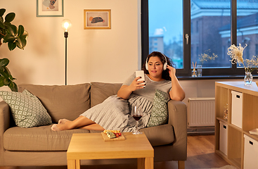 Image showing woman in headphones listens to music on smartphone