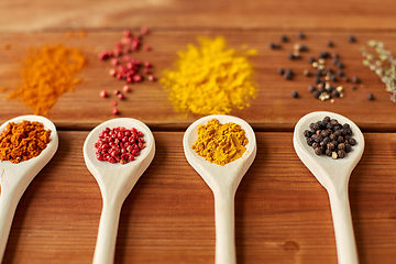 Image showing spoons with different spices on wooden table