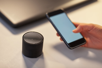 Image showing hand with smartphone and smart speaker at office