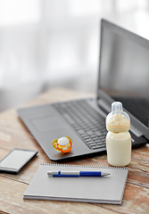 Image showing baby milk formula, laptop and notebook on table