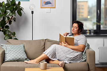 Image showing young woman with diary on sofa at home