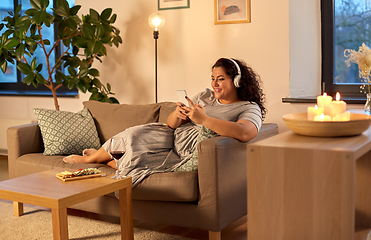 Image showing woman in headphones listens to music on smartphone