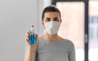 Image showing close up of woman in mask holding hand sanitizer