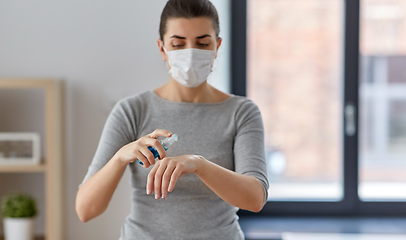 Image showing close up of woman in mask spraying hand sanitizer