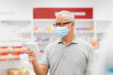 Image showing senior man in medical mask with drug at pharmacy