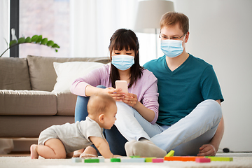 Image showing family with baby in medical masks at home