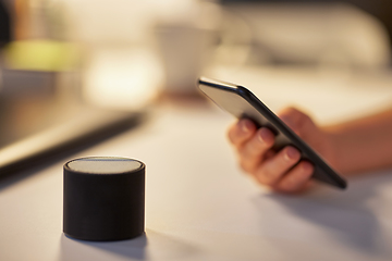 Image showing hand with smartphone and smart speaker at office