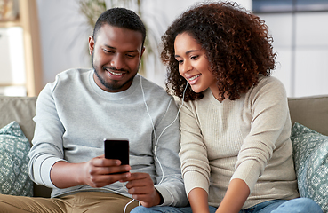 Image showing happy couple with smartphone and earphones at home