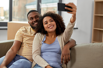 Image showing happy couple moving to new home and taking selfie