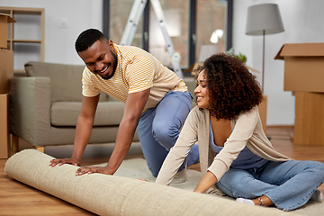 Image showing happy couple with carpet moving to new home