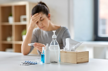 Image showing medicines and sick woman with thermometer at home