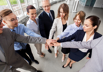 Image showing happy business people stacking hands at office