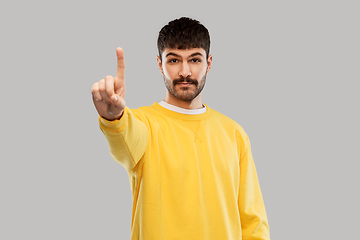 Image showing young man in yellow sweatshirt showing one finger