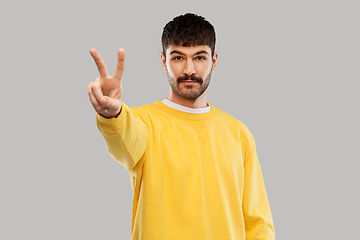 Image showing young man showing peace over grey background