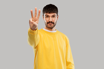 Image showing man in yellow sweatshirt showing three fingers