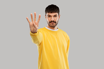 Image showing man in yellow sweatshirt showing four fingers