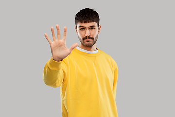 Image showing serious young man showing stop gesture