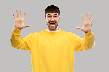 Image showing smiling young man showing his hand or ten fingers