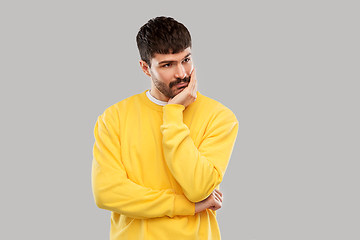 Image showing sad young man in yellow sweatshirt thinking